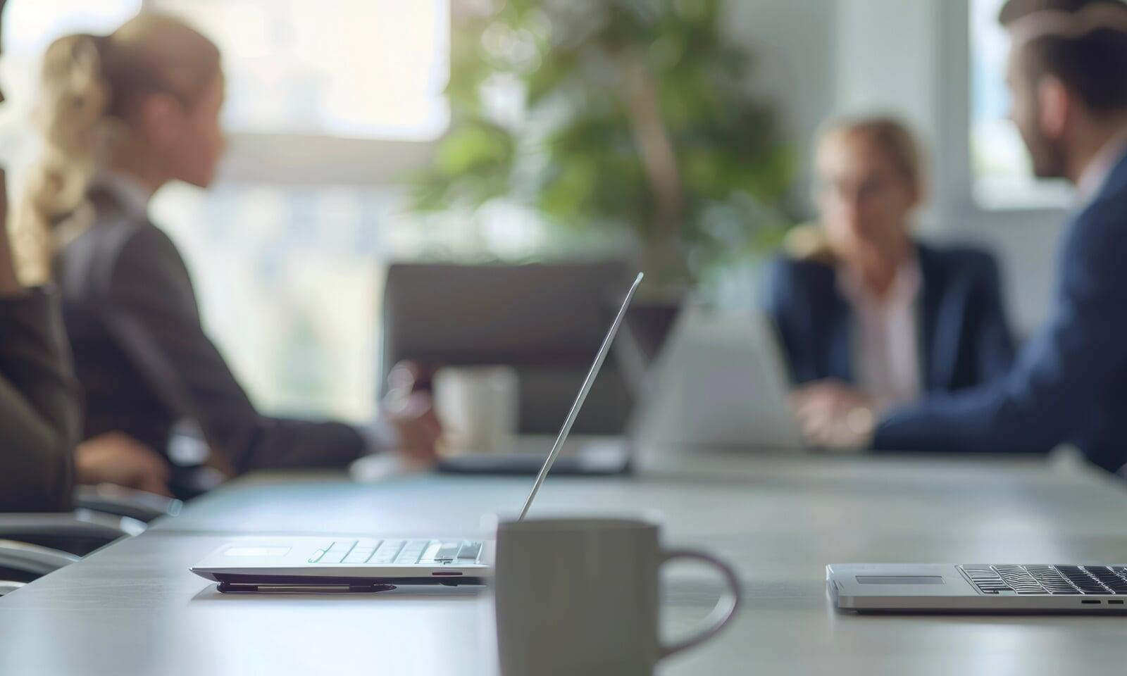 business meeting men women desk macbook laptops