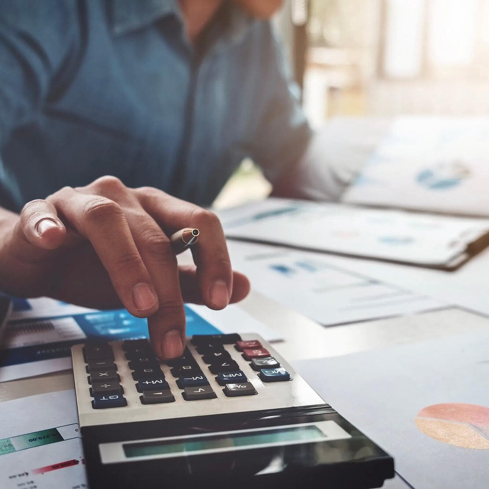 person typing on a calculator in order to balance business expenses
